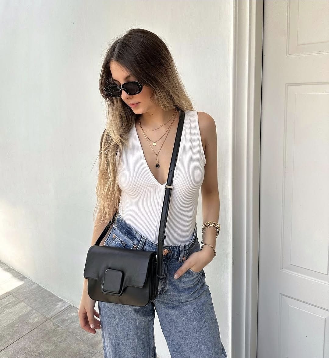 Modelo con bolso cruzado negro clásico y gafas de sol rectangulares